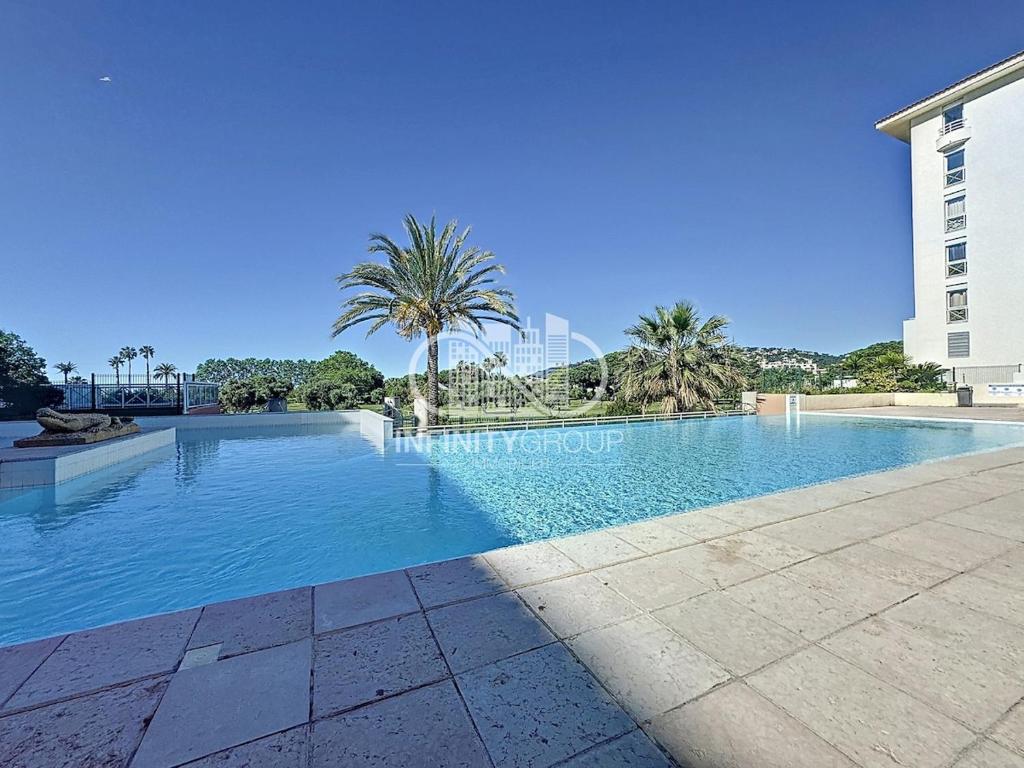 une piscine avec des palmiers et un bâtiment dans l'établissement 2P 5 min de la plage - Juan-les-Pins, à Antibes