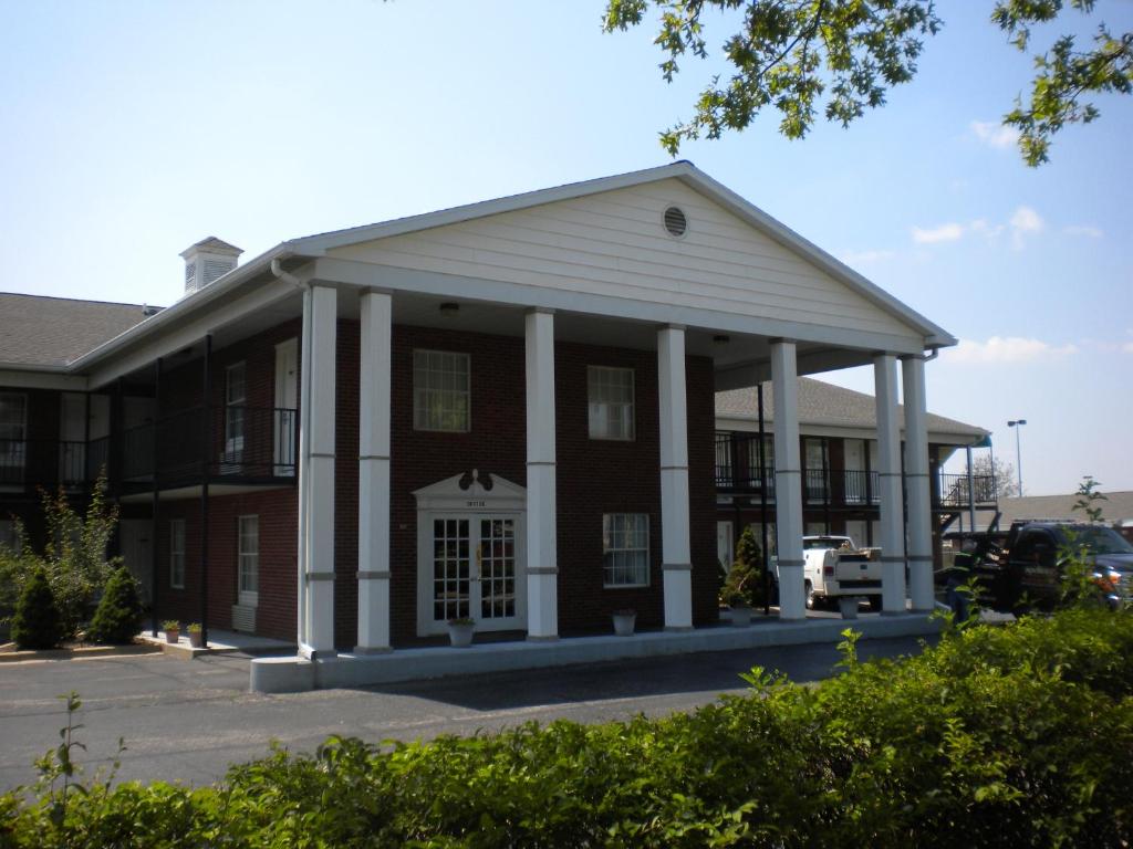 un edificio antiguo con un porche en un aparcamiento en First Heritage Inn Rantoul, en Rantoul