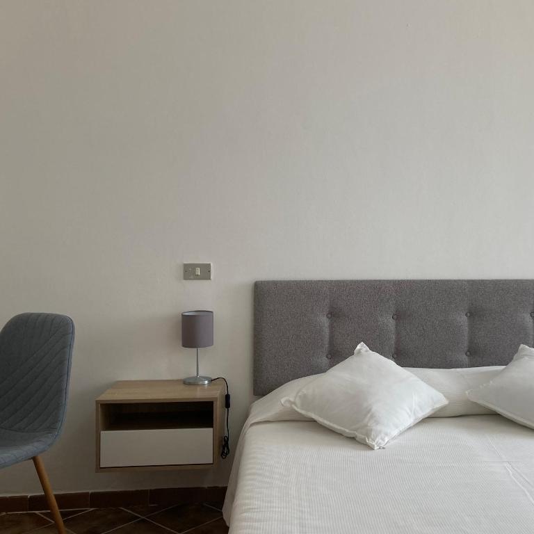 una camera da letto con un letto bianco e una sedia di En-suite Triple Room-Giardino A Mare a Donnalucata