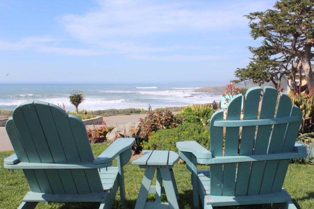 two blue chairs sitting on the grass near the ocean at Cambria Shores Inn in Cambria