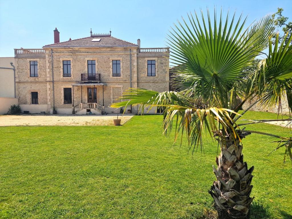 un palmier devant un grand bâtiment dans l'établissement Jolie masdame - Sauzet, à Sauzet