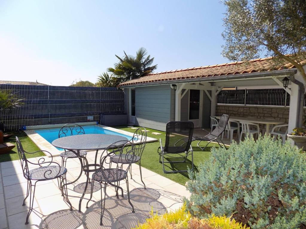 a patio with a table and chairs next to a pool at Les Mathes La Palmyre - MAISON MITOYENNE en PIERRES - avec PISCINE PRIVEE in Les Mathes