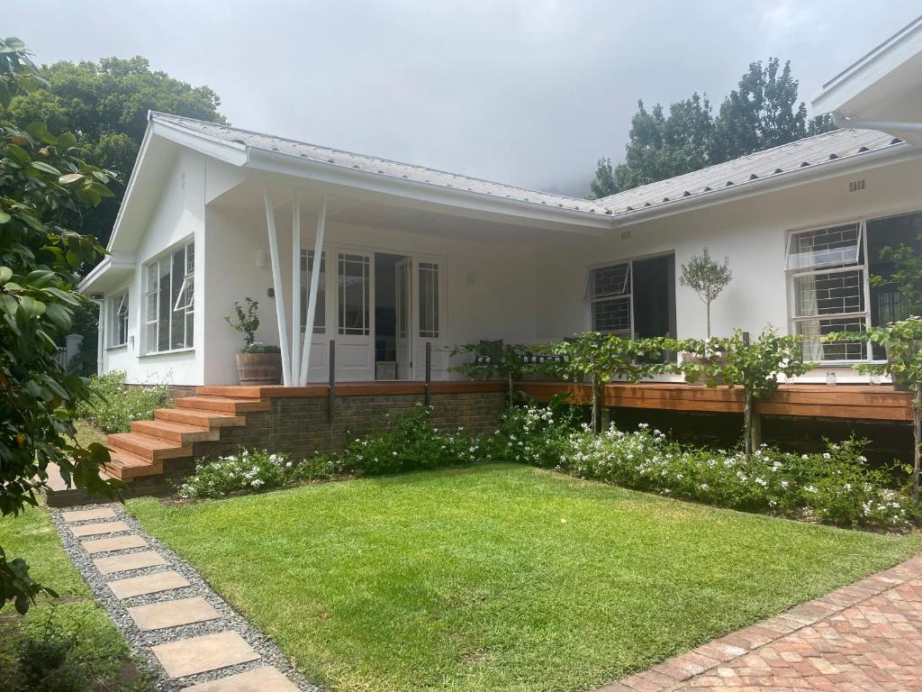 a white house with a lawn in front of it at 8 Sleeper, 4 Bedroom Home in Franschhoek in Franschhoek