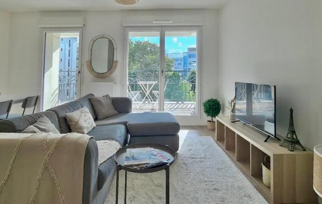 un salon avec un canapé et une télévision dans l'établissement Le Central - Bel appartement lumineux proche Paris, à Saint-Ouen