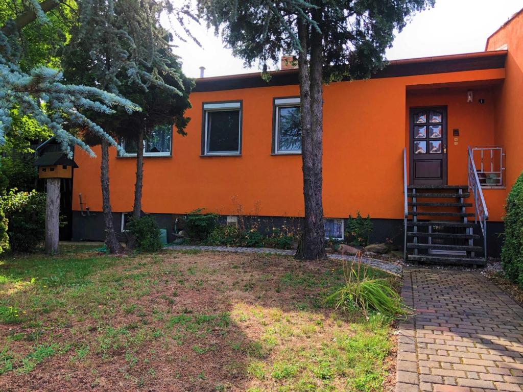 an orange house with a porch and trees at Ferienhaus am Wiesenweg in Hosena