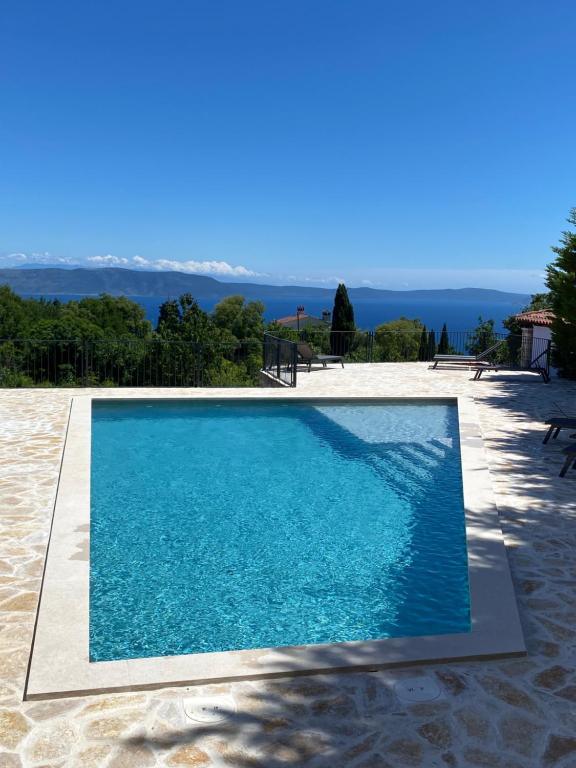 a blue swimming pool with a view of the ocean at Villa Castelina Part II of twin house in Vicani