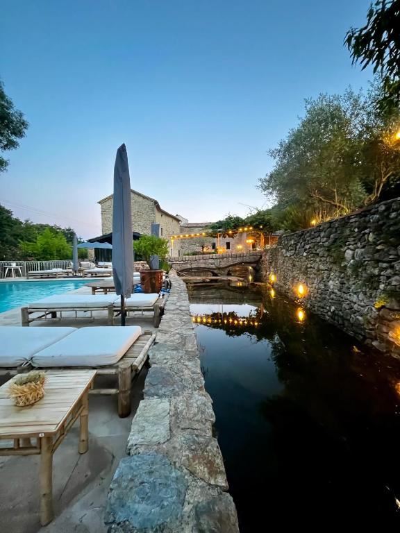 une piscine avec un mur de pierre à côté d'une rivière dans l'établissement Le Moulin de l'Auzonnet, à Les Mages
