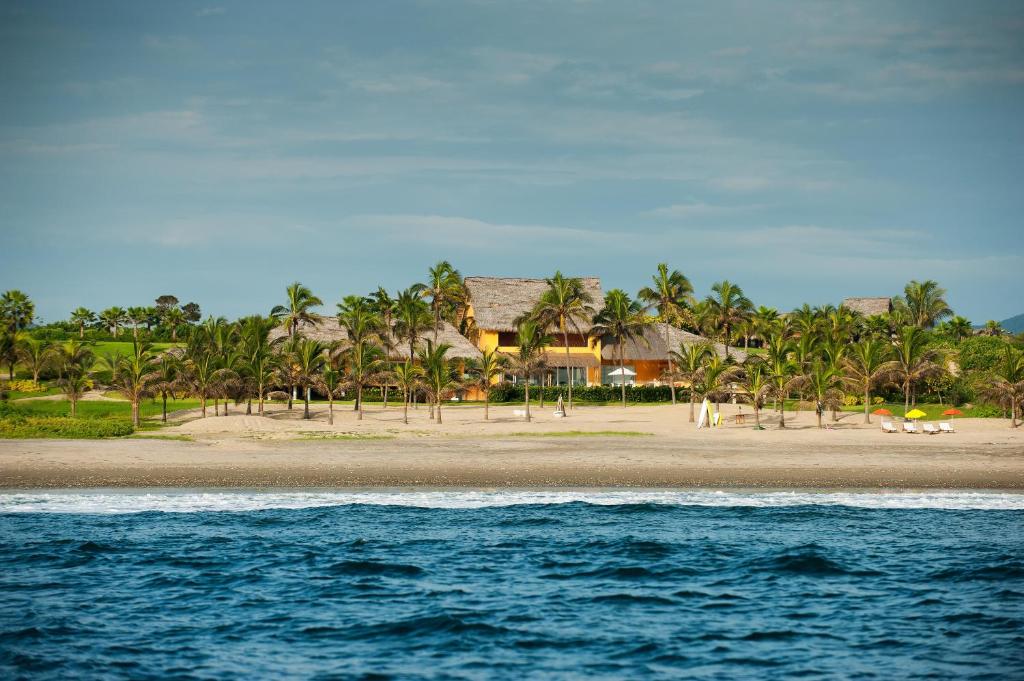 uma praia com palmeiras e casas e o oceano em Tanusas Retreat & SPA em Puerto Cayo