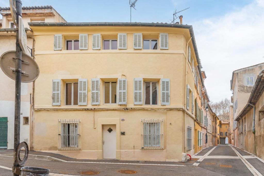 ein gelbes Gebäude mit weißen Fensterläden an einer Straße in der Unterkunft Lisse Studios in Aix-en-Provence