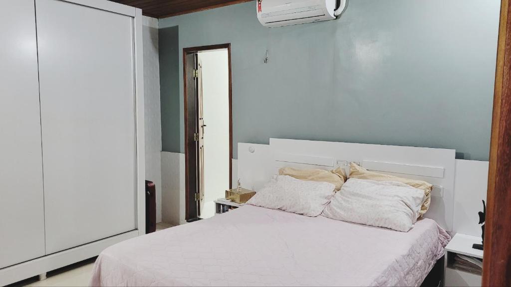 a bedroom with a white bed with two pillows at Casa Luxo Ampla Completa COP30 in Ananindeua