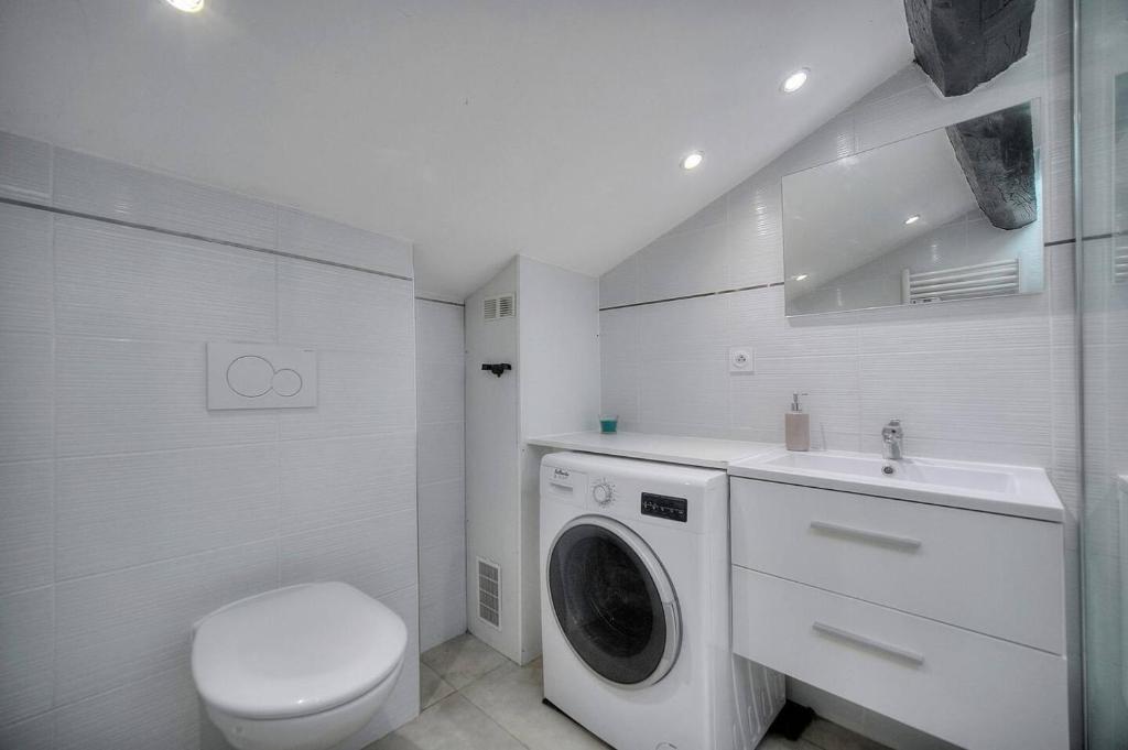La salle de bains blanche est pourvue d'un lave-linge et de toilettes. dans l'établissement Studio Cannes, à Cannes