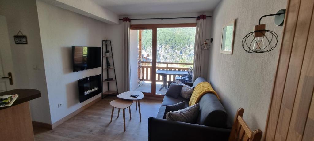 un salon avec un canapé bleu et un balcon dans l'établissement Les Orres 1800 vue montagne 4 à 6 couchages avec parking, aux Orres