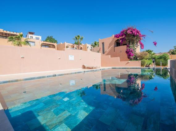 una piscina con un edificio y flores en él en Appartement résidence, en Taghazout