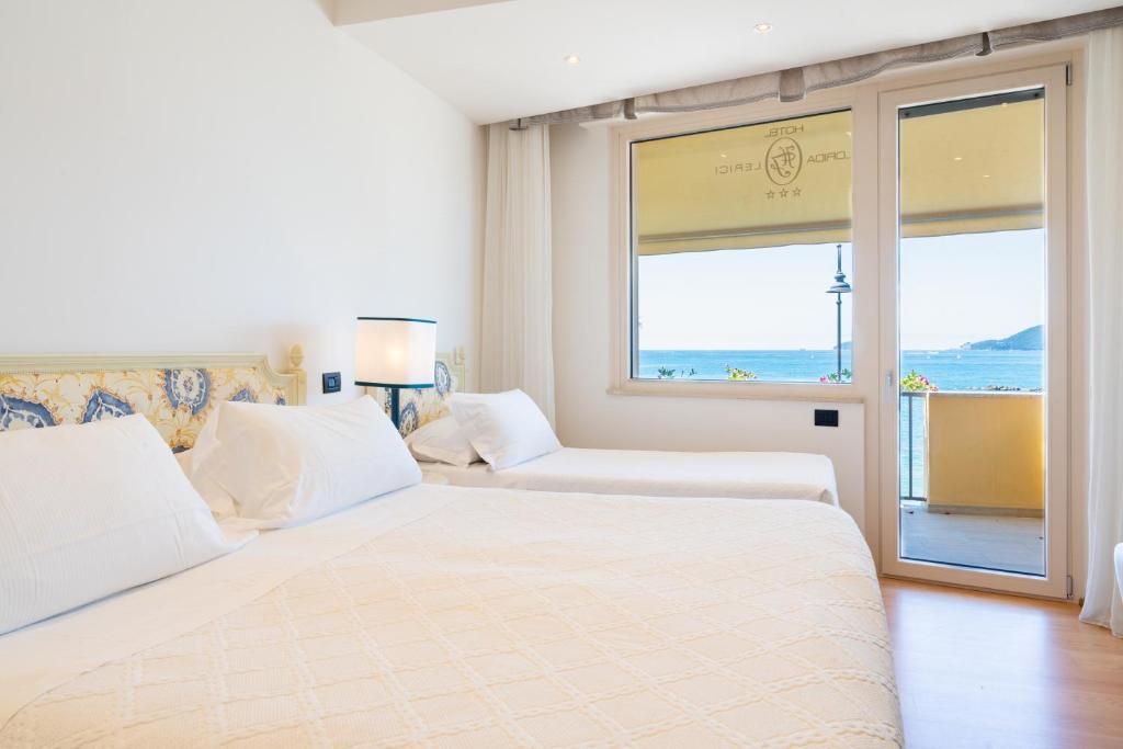 a white bedroom with a large bed and a window at Hotel Florida Lerici in Lerici