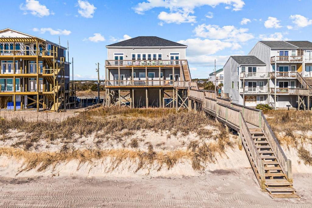 a house on the beach next to a building at Ocean Charm in North Topsail Beach