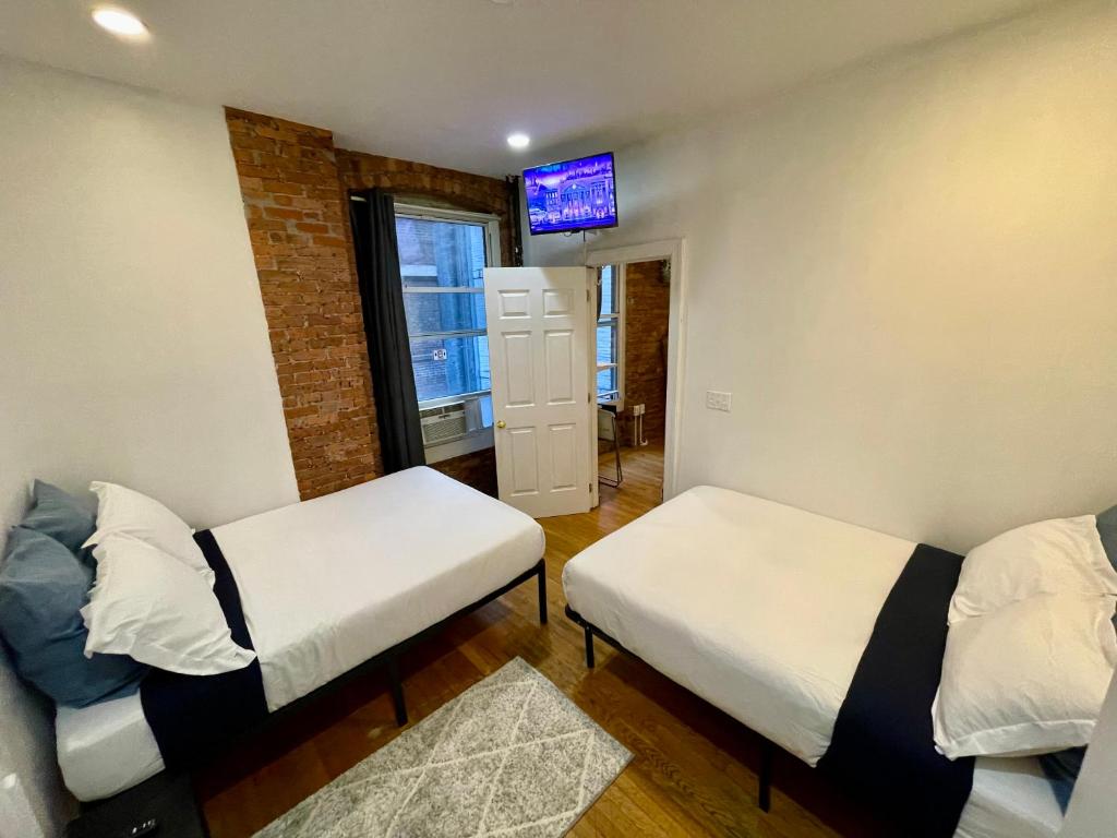 a room with two beds and a tv on the wall at Nestel Nest 1 bedroom apartment in New York