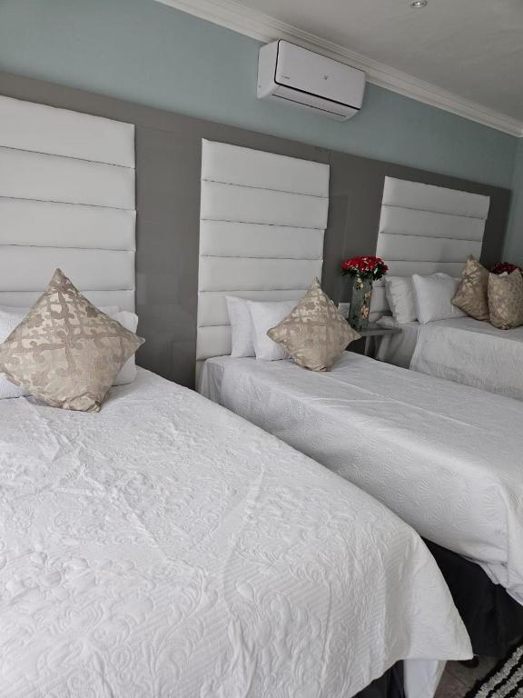 two beds in a room with white sheets and pillows at Elitha Boutique Bed and Breakfast in Mogwase