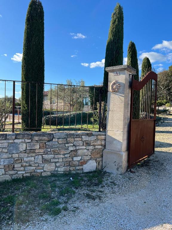 une porte en bois avec une clôture en pierre et des arbres dans l'établissement GRAIN de SOLEIL, à Orgnac-lʼAven