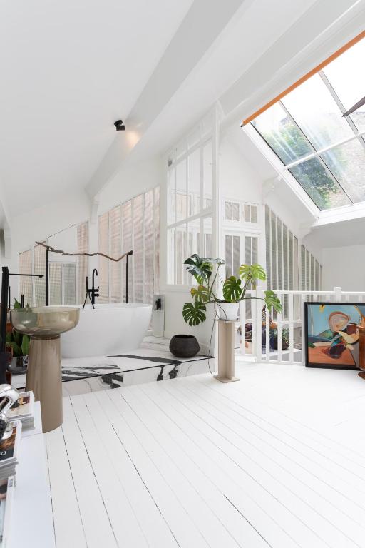 La salle de bains blanche est pourvue d'une lucarne et d'un lavabo. dans l'établissement Atelier Auteuil Luxury, à Paris