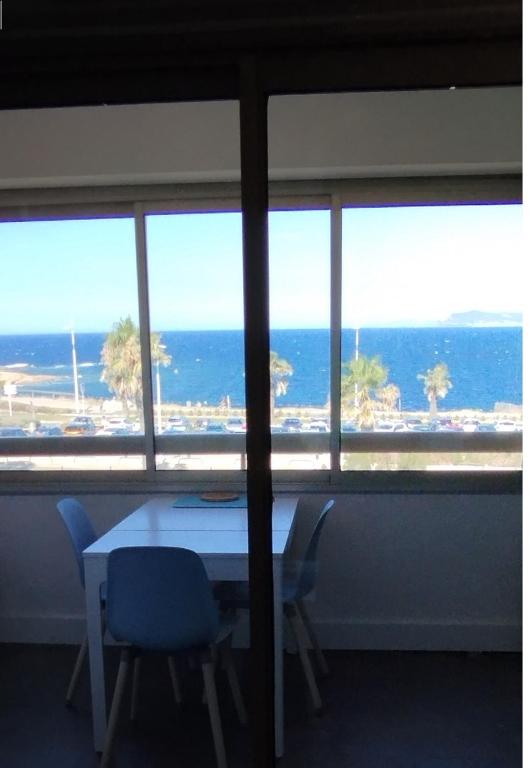 une table et des chaises dans une pièce avec vue sur l'océan dans l'établissement SIX-FOURS vue mer et situé devant la plage, à Six-Fours-les-Plages