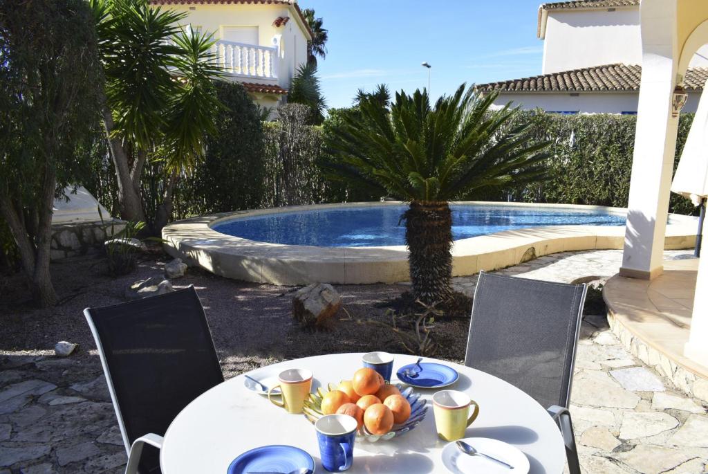 a table with a plate of fruit next to a pool at Anacasa Picasso Oliva Nova CH1400 in Oliva