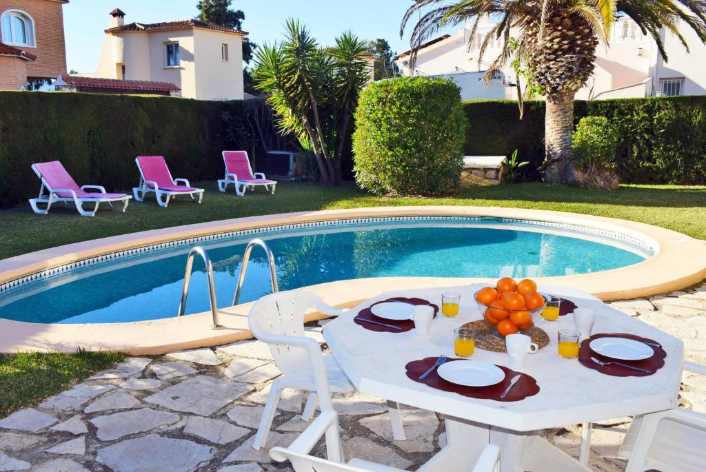 einen Tisch und Stühle vor einem Pool in der Unterkunft Anacasa Villa Renoir Oliva Nova CH1015 in Oliva