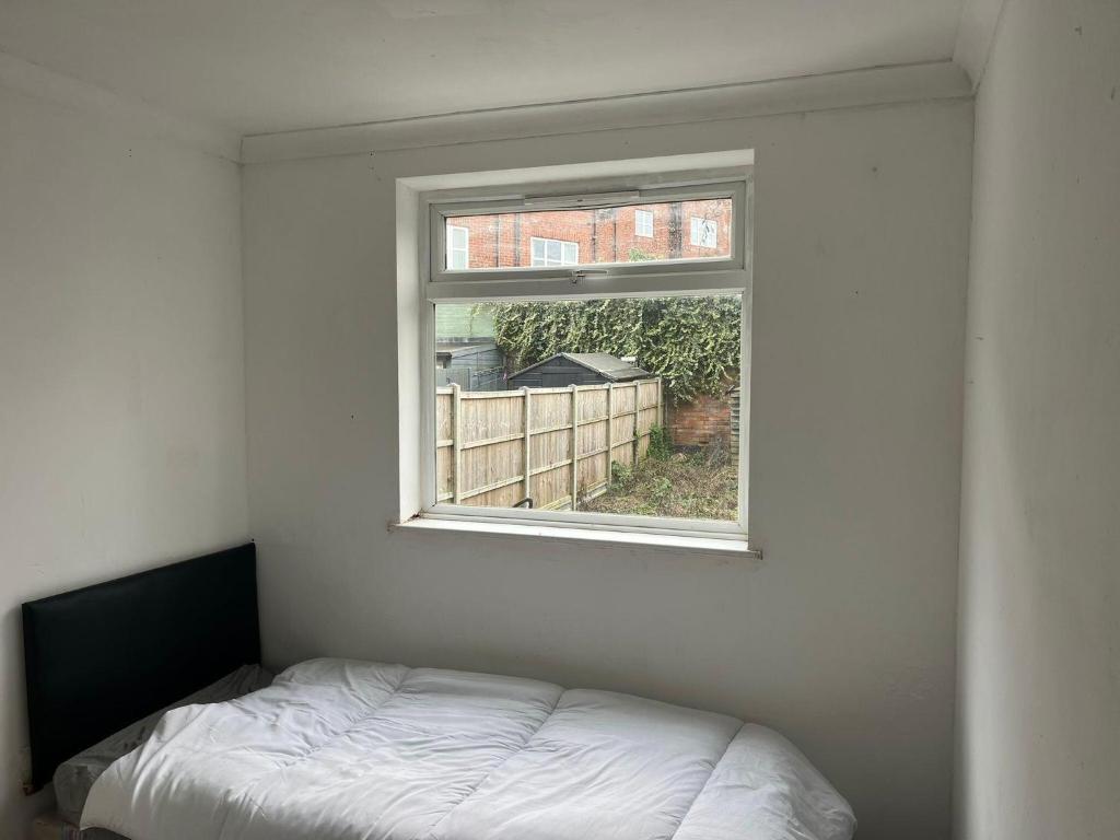 une chambre blanche avec une fenêtre et un lit dans l'établissement Garden Street Retreat in Wigston, à Glen Parva