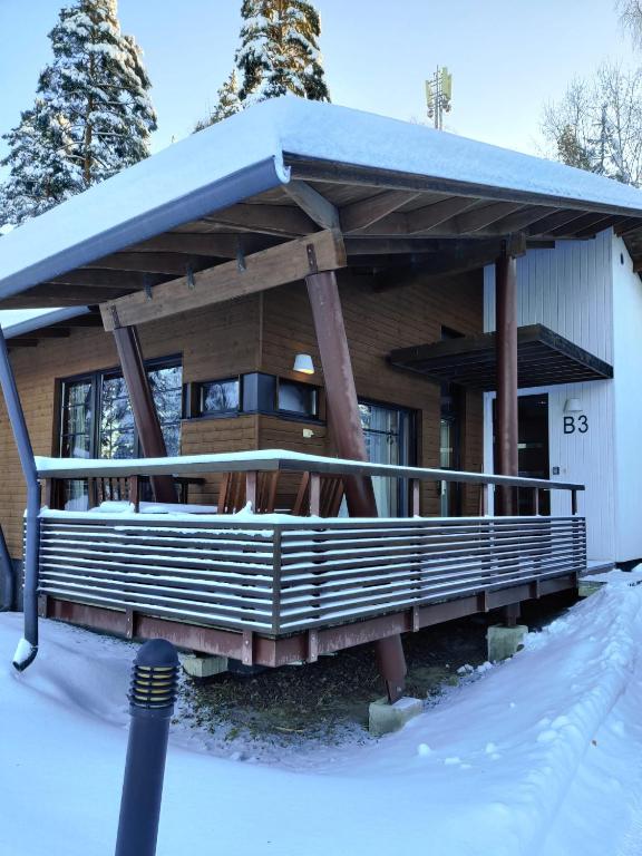 a house with a covered porch in the snow at Kylpyla SPA, Saimaa Villa B3 in Imatra