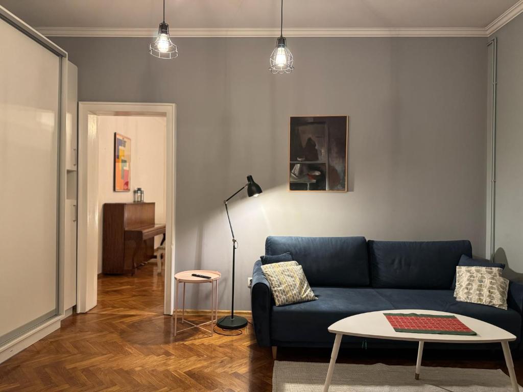 Una sala de estar con un sofá azul y una mesa. en Apartamenty Zasanie, en Przemyśl