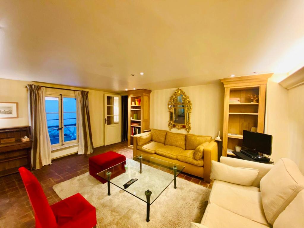 - un salon avec un canapé jaune et des fauteuils rouges dans l'établissement Appartement Musée du Louvre Paris, à Paris