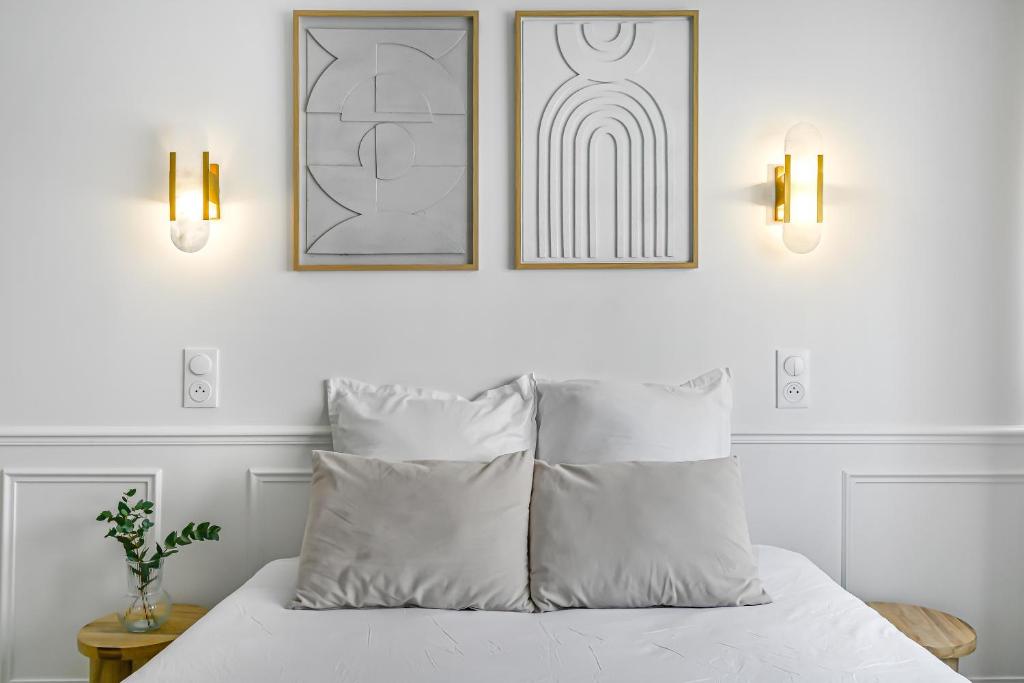 - une chambre blanche avec deux photos au-dessus d'un lit dans l'établissement JIJI Suites, à Combs-la-Ville