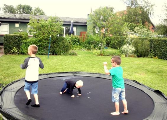 Tres niños jugando en un trampolín en Holiday Home Kirkeby Feriehus, en Roslev