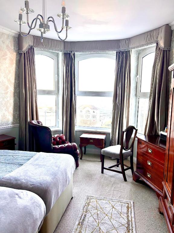 a bedroom with two beds and a dresser and windows at Albany Lodge in Portrush