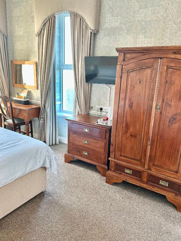a bedroom with a wooden dresser and a large wooden cabinet at Albany Lodge in Portrush