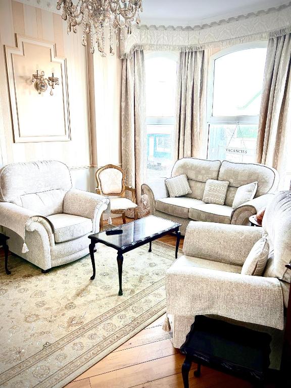 a living room with white furniture and a chandelier at Albany Lodge in Portrush