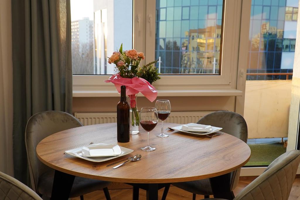 a wooden table with a vase of flowers and wine glasses at Simply Apartament - Symfonia z parkingiem in Toruń