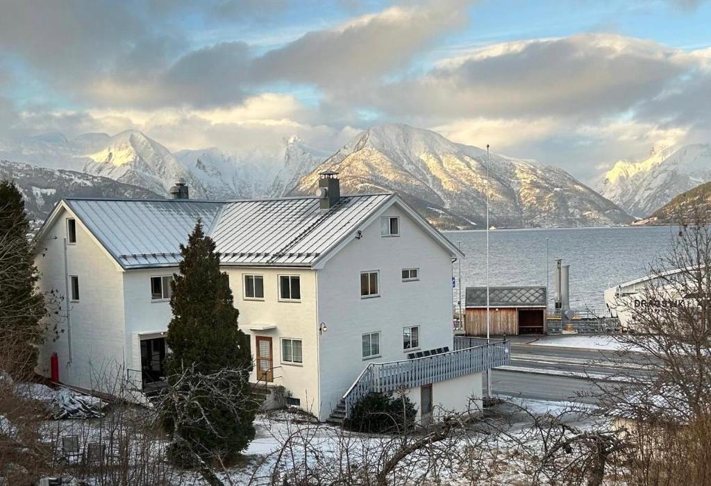 a white house in front of a lake and mountains at Sognefjord Gjesteheim in Vangsnes