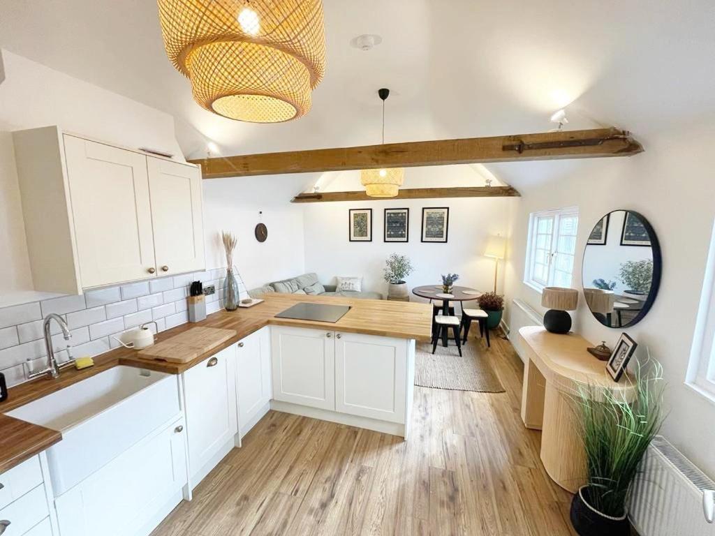 a kitchen with white cabinets and a dining table at Charming, brand new townhouse near the sea in Hythe