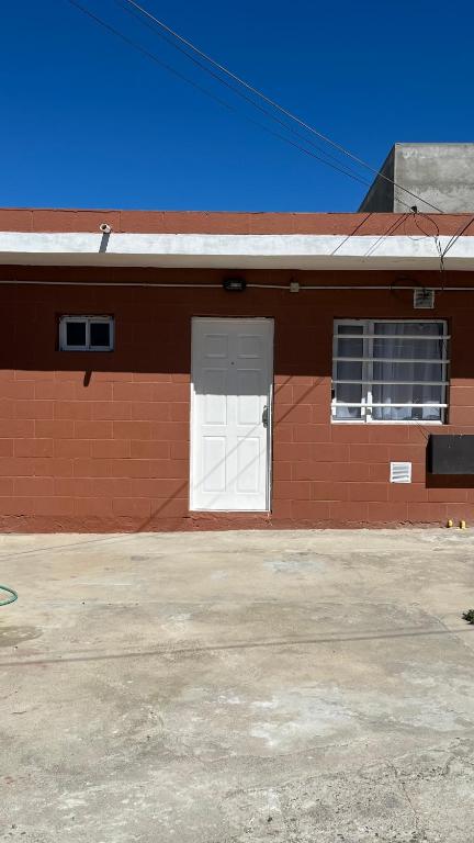 a red brick building with a white door at Maximina Home in Comodoro Rivadavia