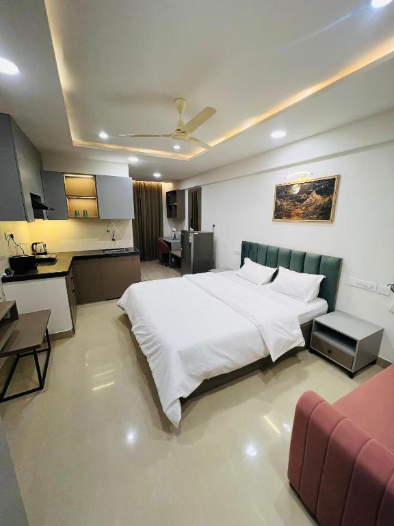 a bedroom with a large white bed and a kitchen at The Sleepy Monkey in Jaipur
