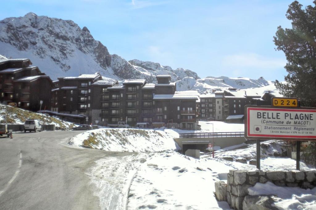 un bâtiment sur une route enneigée avec un panneau dans l'établissement Studio cosy à Mâcot-la-Plagne 24 m² avec vue montagne, à Mâcot La Plagne