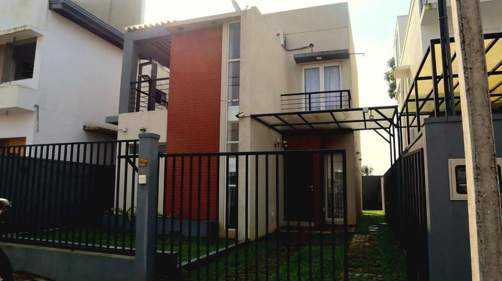 ein Haus mit einem schwarzen Tor und einem Gebäude in der Unterkunft Fully Furnished 3BR Tourist House in Golf Resort Apartments in Gonapola