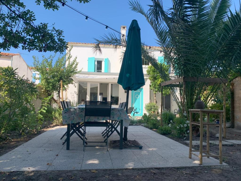 une table et un parasol devant une maison dans l'établissement Les Louisettes, à Grand-Village-Plage