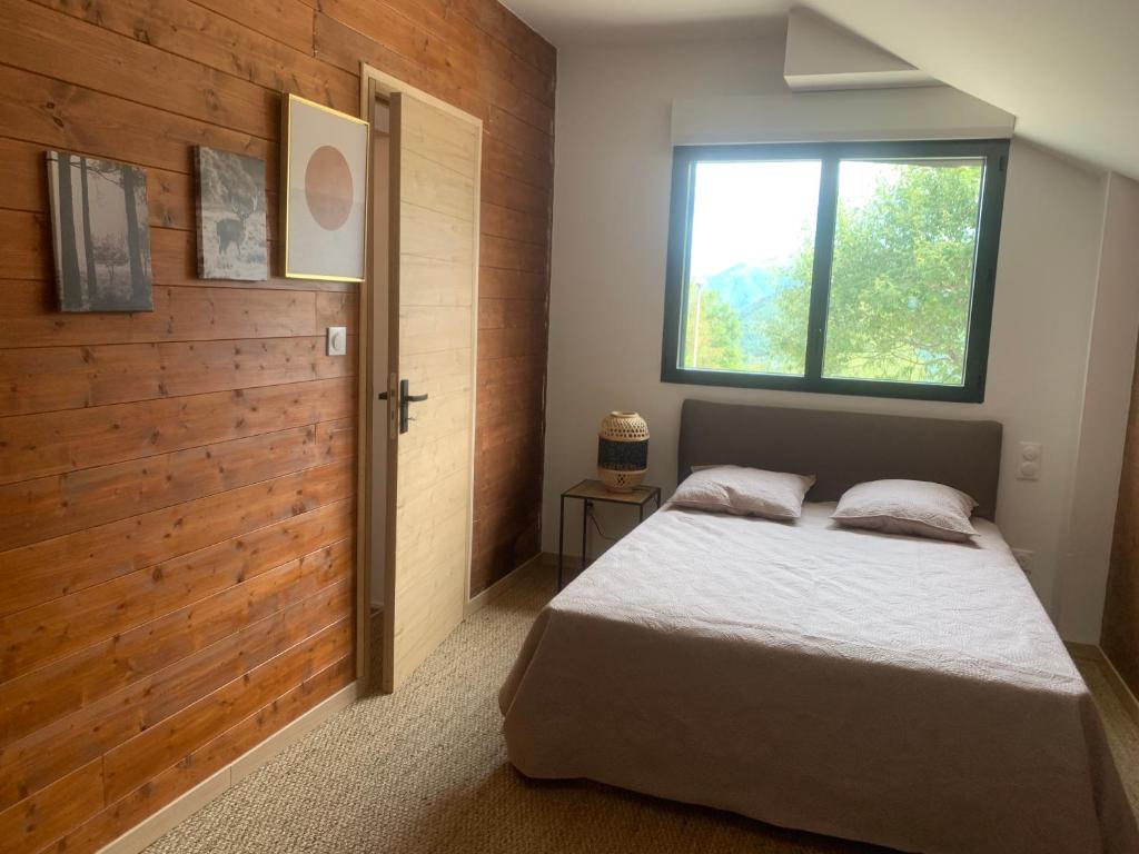 - une chambre avec un lit et un mur en bois dans l'établissement L'Aiglon, à Ax-les-Thermes