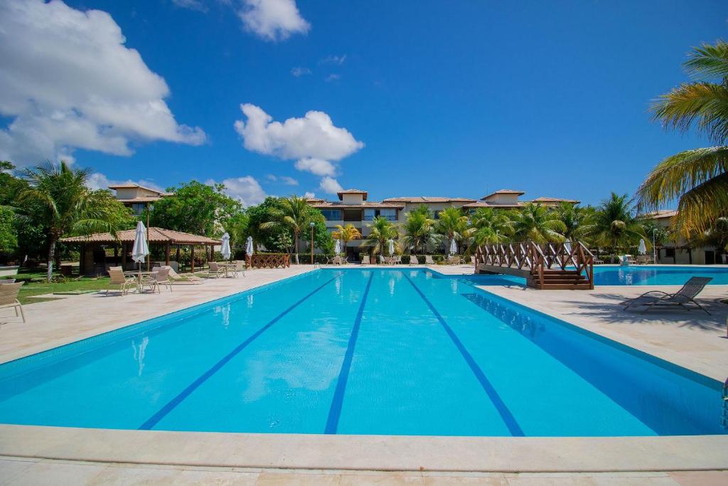 a pool at the resort with chairs and palm trees at GB20 Lindo Apto 3/4 - Genipabu Club House in Monte Gordo