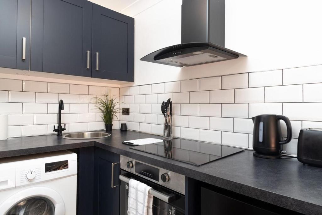 a kitchen with black cabinets and a washer and dryer at Studio 5A Willow Brook in Bedworth