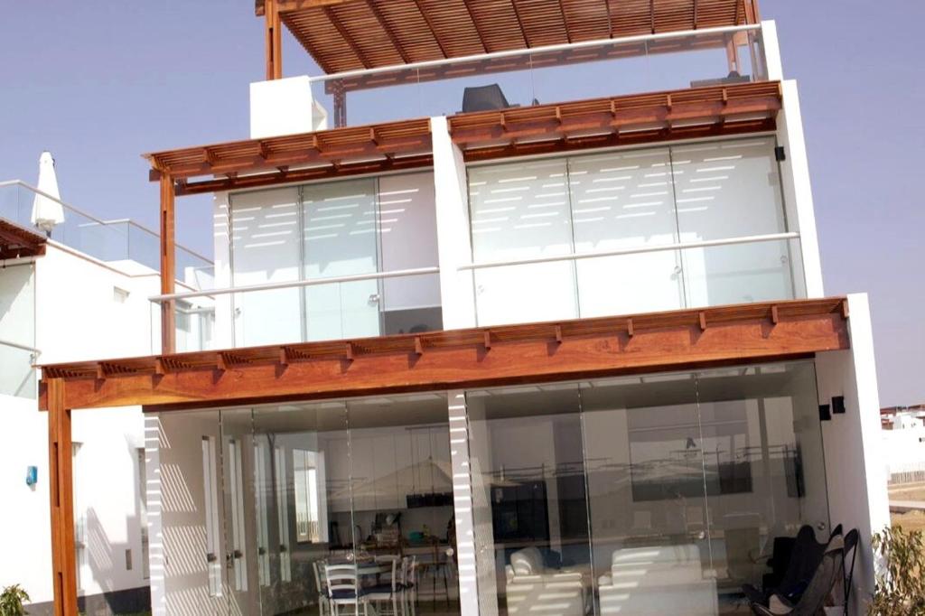 a house with large glass windows and a deck at Casa de Playa - Asia - SELENE beach house in Asia