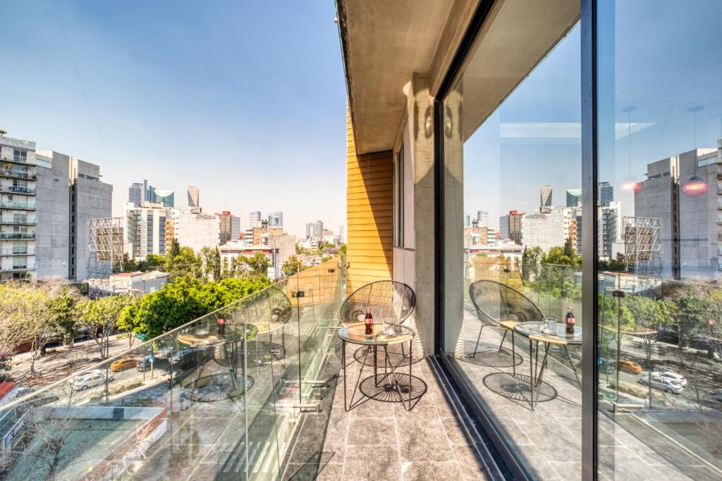 een balkon met twee stoelen en uitzicht op de stad bij MEDELLIN by Mr W in Mexico-Stad
