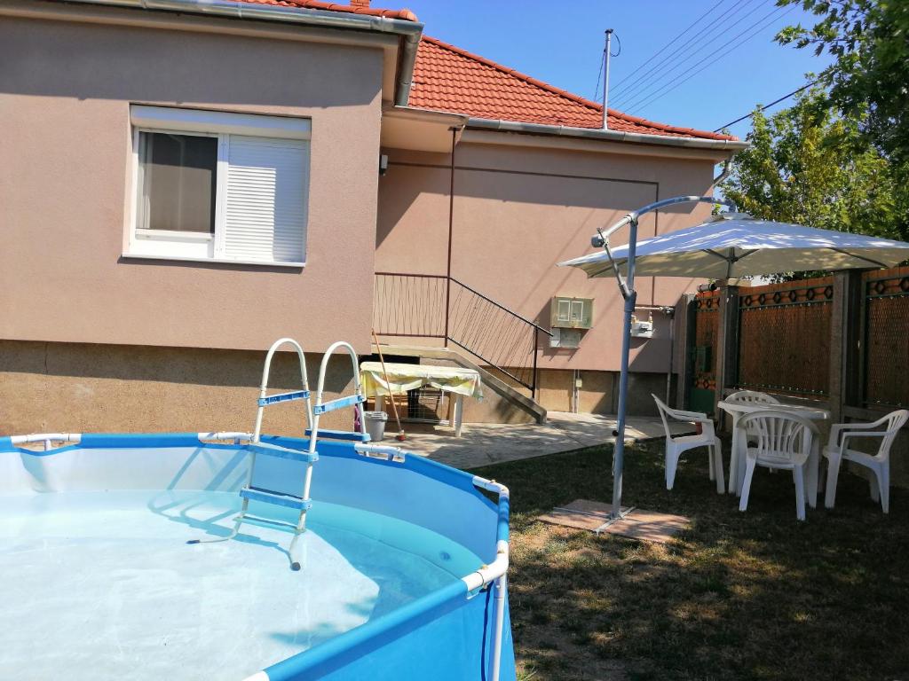 a swimming pool with a table and an umbrella at Új Lilla Apartman in Keszthely