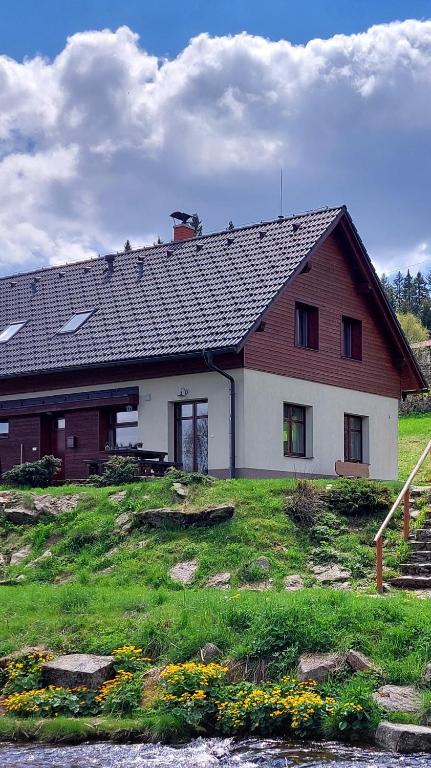 dom na wzgórzu z trawnikiem w obiekcie Wellness Chata Rosnatka w mieście Kvilda
